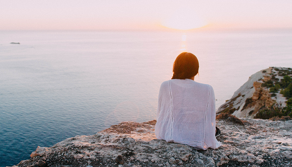 Woman on a rock ledge over looking the sea | Workplace Mental Health Program | Benefits by Design