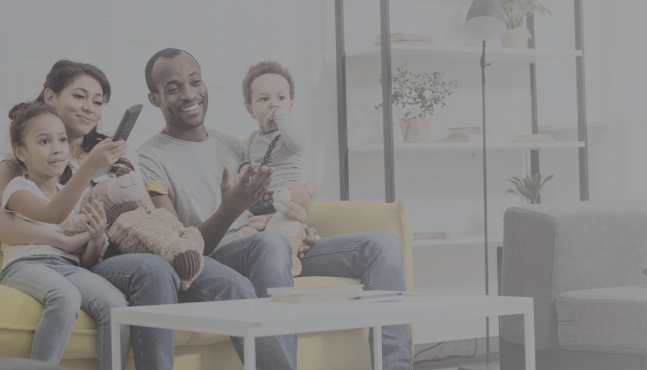 Family looking at a cellphone while sitting on a couch.