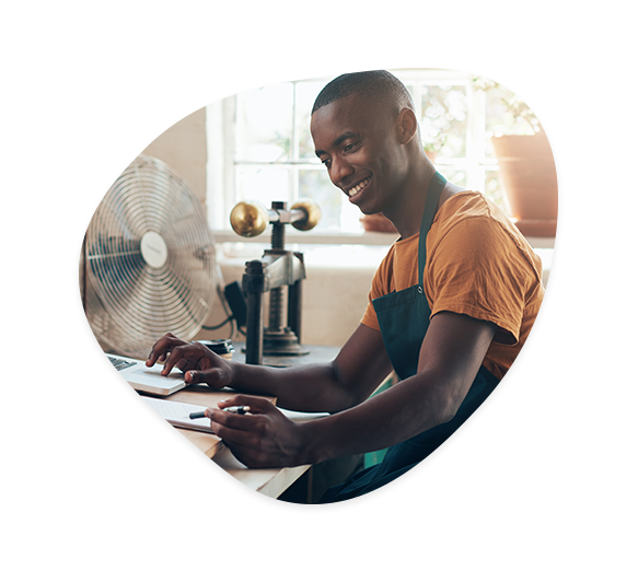 Man smiling, working at his computer and writing.
