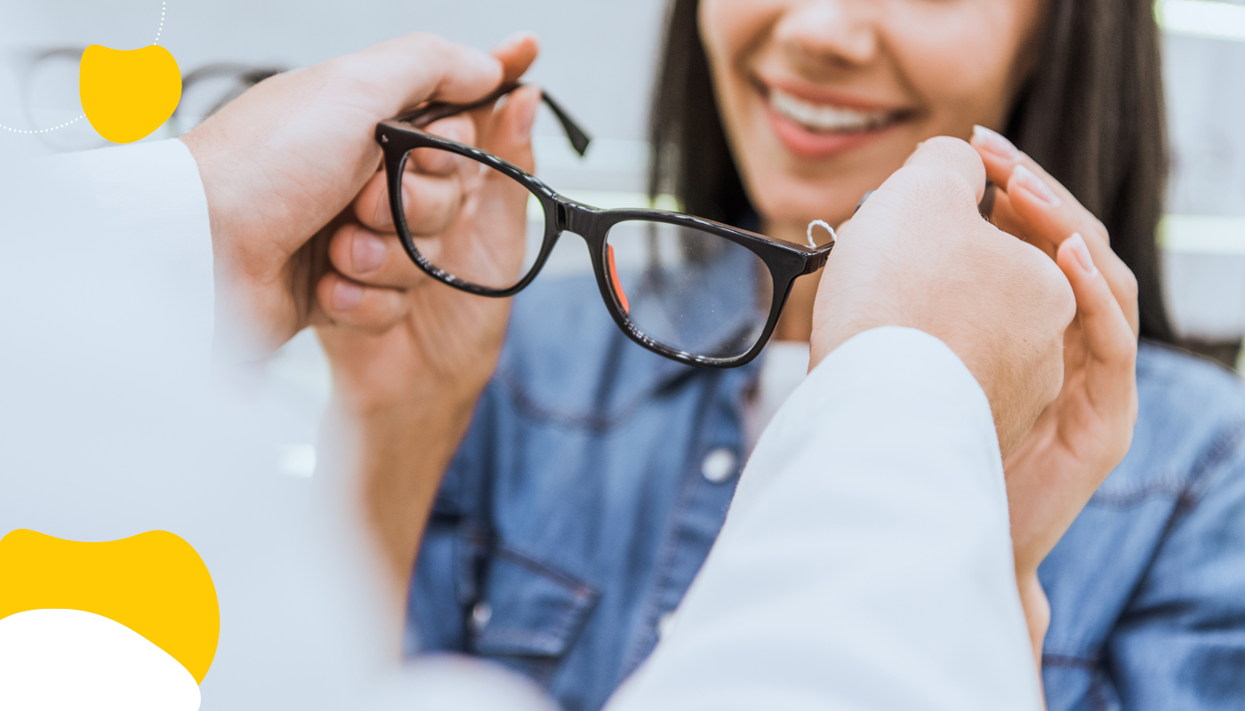 Woman smiling as a doctor helps her put on glasses | HCSA utilization | Benefits by Design