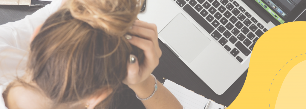 Woman cradling her head in front of a laptop.