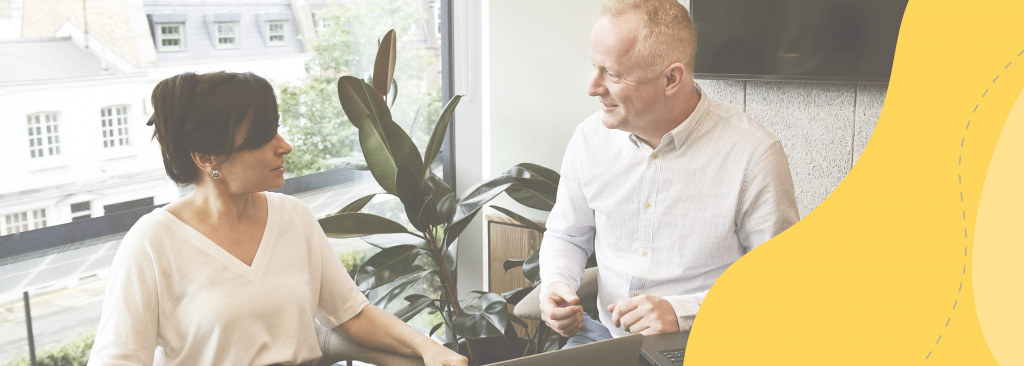 A man and a woman talking in an office environment.