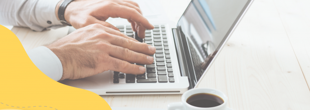 Man working from home, typing on a laptop with a cup of coffee beside him.