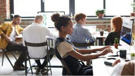 Happy woman working in a crowded office with large windows for optimal employee health
