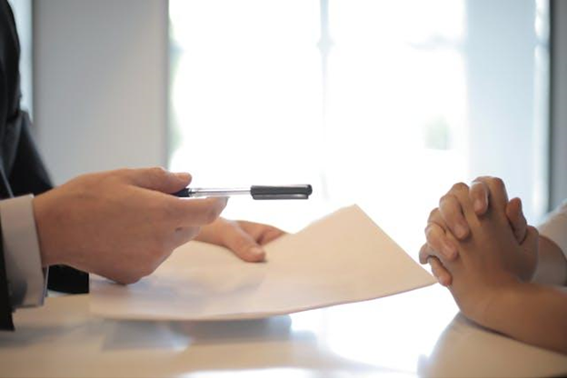 a man holding a paper and pen while talking to someone