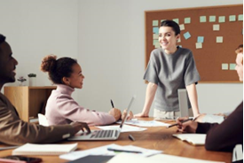 A woman smiling and looking at other people in the office.